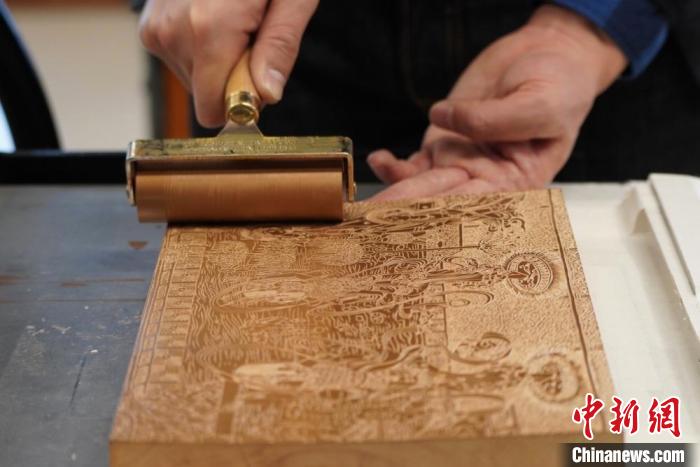 圖為徐晉林工作室工作人員正在給雕好壁畫的版面滾油墨?！【琶赖┰?　攝