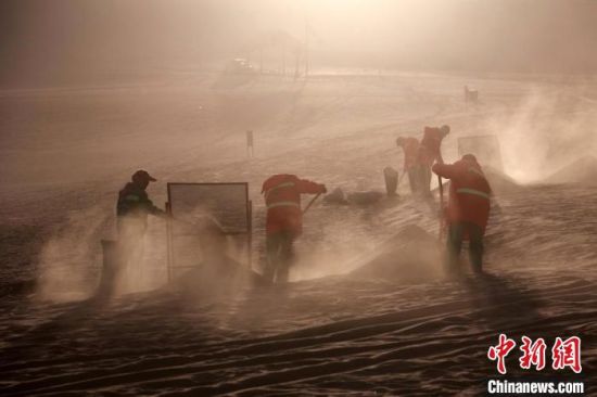 圖為敦煌市鳴沙山月牙泉景區(qū)“駱駝保姆”清理駱駝糞便?！垥粤?攝