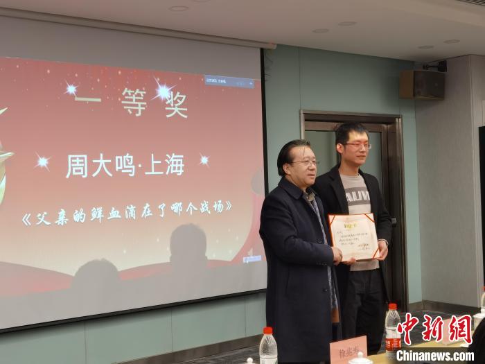 圖為作家、西北師范大學(xué)新聞與傳媒學(xué)院院長(zhǎng)徐兆壽頒發(fā)一等獎(jiǎng)證書(shū)，代領(lǐng)獎(jiǎng)?wù)呱吓_(tái)領(lǐng)獎(jiǎng)?！钅?攝