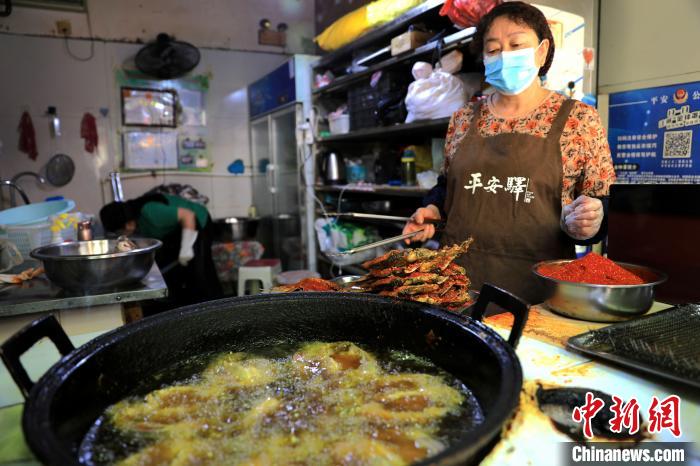 圖為平安驛·河湟民俗文化體驗(yàn)地內(nèi)的商戶炸干板魚。　薛蒂 攝