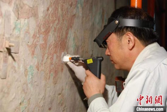 敦煌研究院研究員樊再軒進(jìn)行壁畫修復(fù)。(資料圖)張?jiān)莆?攝